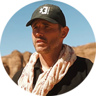 一个戴着黑色帽子和围巾的男人站在岩石景观前。